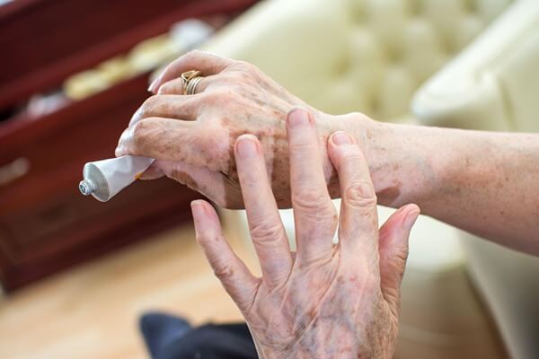 Elderly woman's hands putting on lotion