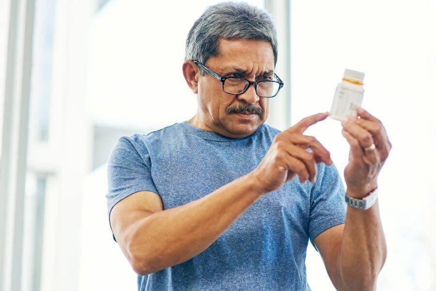 elderly man reading the back of a tablet bottle