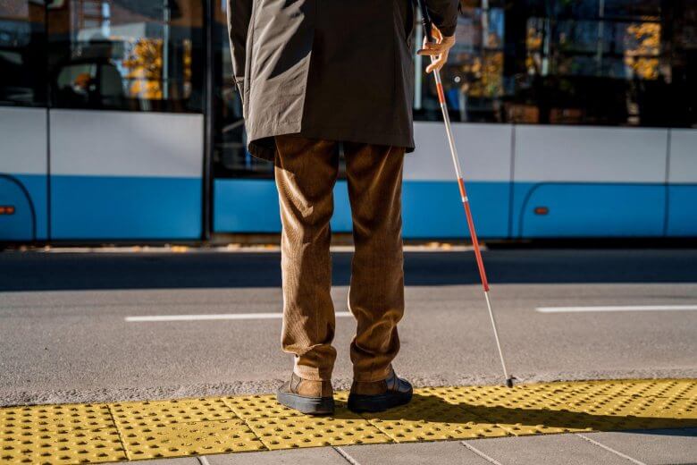 blind man with a cane waiting to cross the street
